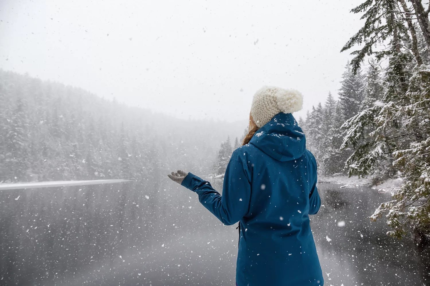 Woman by the icy lake  Explore Magazine Woman enjoying the beautiful Canadian Winter Landscape during a snowy day. Taken near Squamish and Whistler, North of Vancouver, BC, Canada.